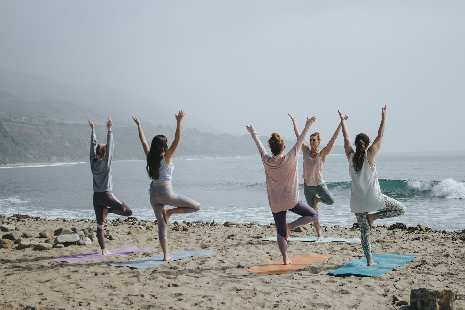 Practitioner holding a yoga pose on the beach at sunrise